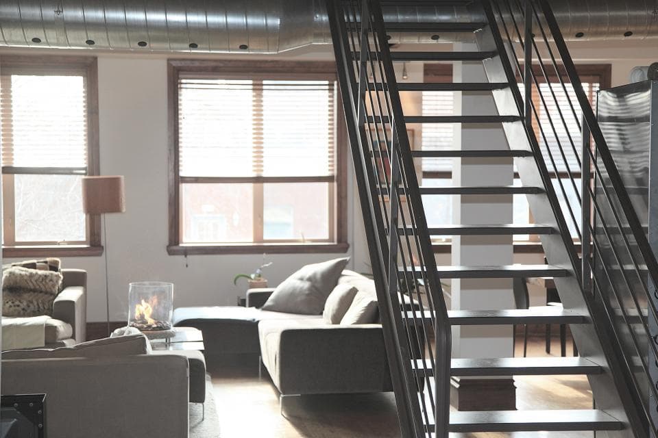 Open-plan loft with tall windows and a steel staircase