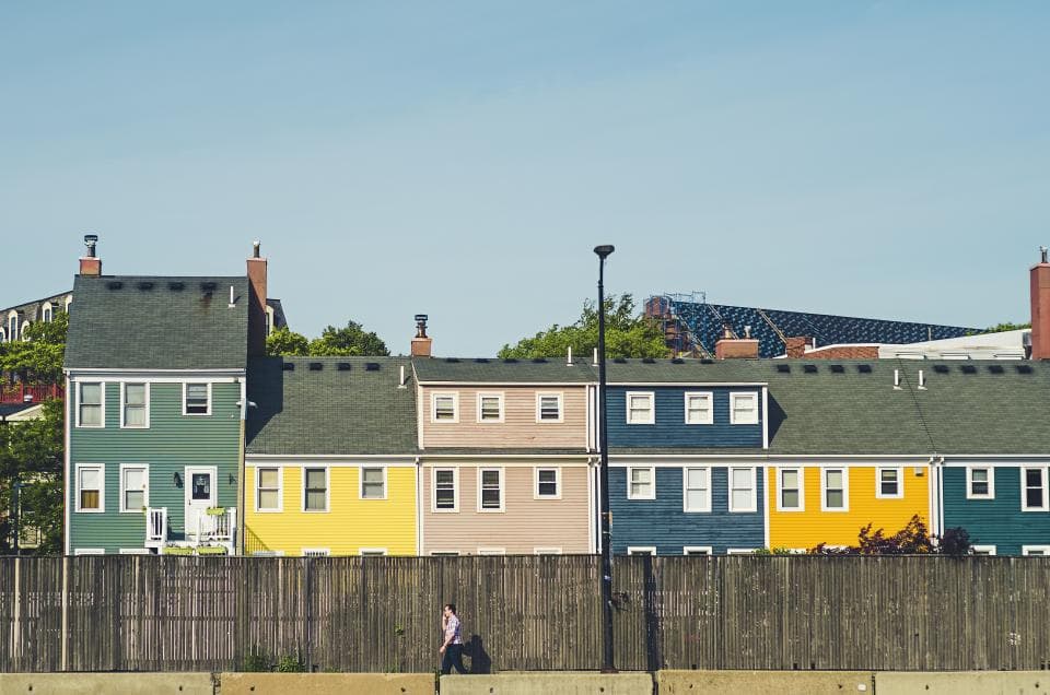 A row of colourful two-storey houses behind a wooden fence