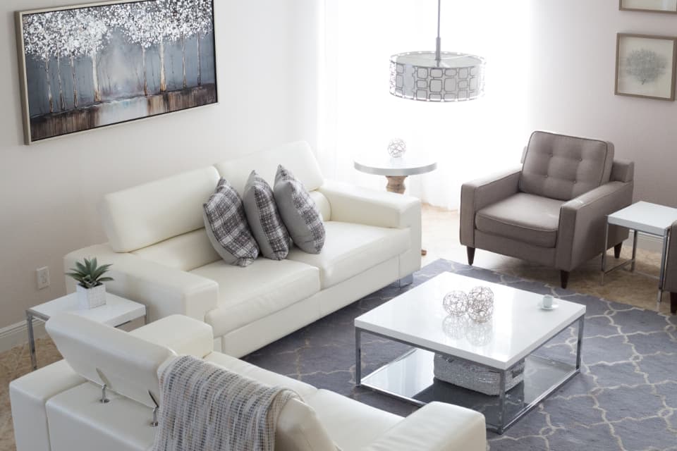 Furnished living room with white sofas and a glass coffee table